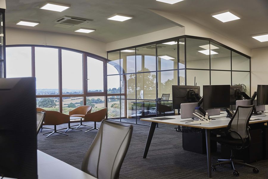 Desks beside the curved windows of a Grovelands office, looking out over the Northamptonshire countryside